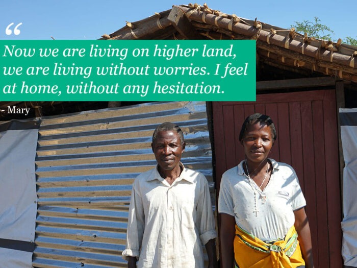 man and woman standing outside home iwth tin walls in malawi