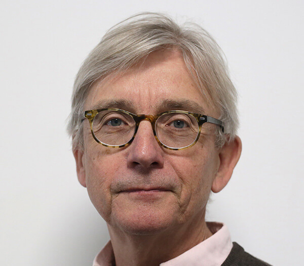 Man wearing glasses in front of a cream background